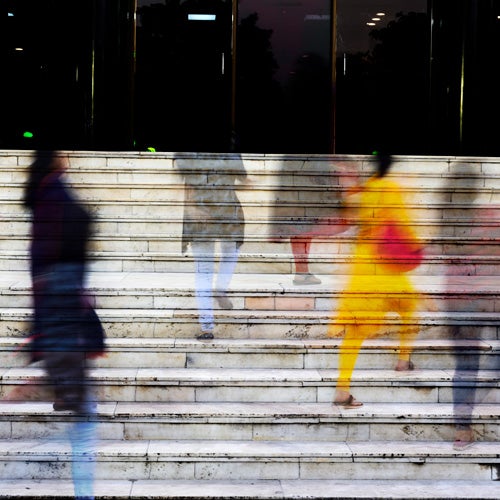 People walk up stone steps in a flurry of activity.